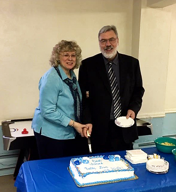 Hinka and David Gilbert cutting the cake at their retirement party