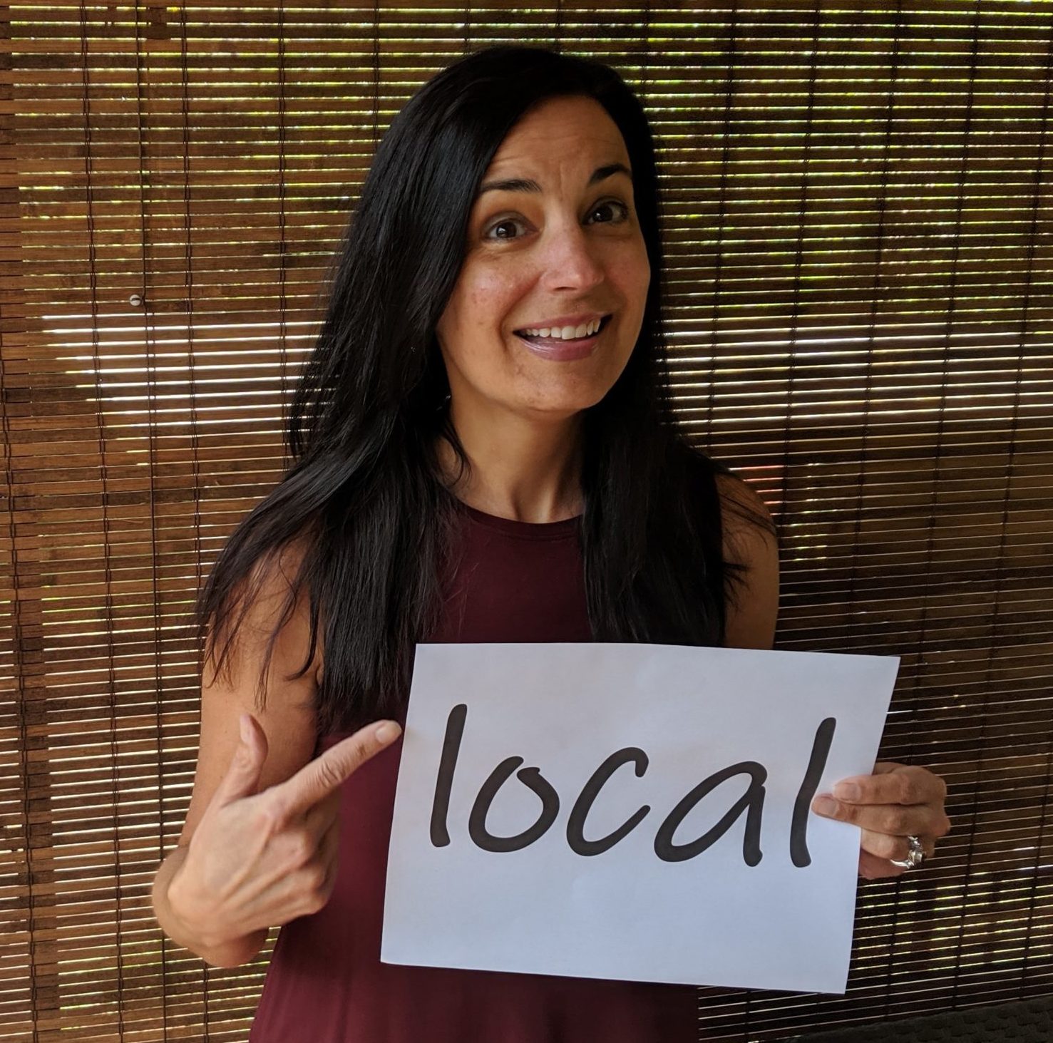 portrait of Elizabeth Mullins holding a sign saying "local"