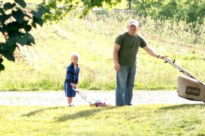 Father and son mowing the lawn together