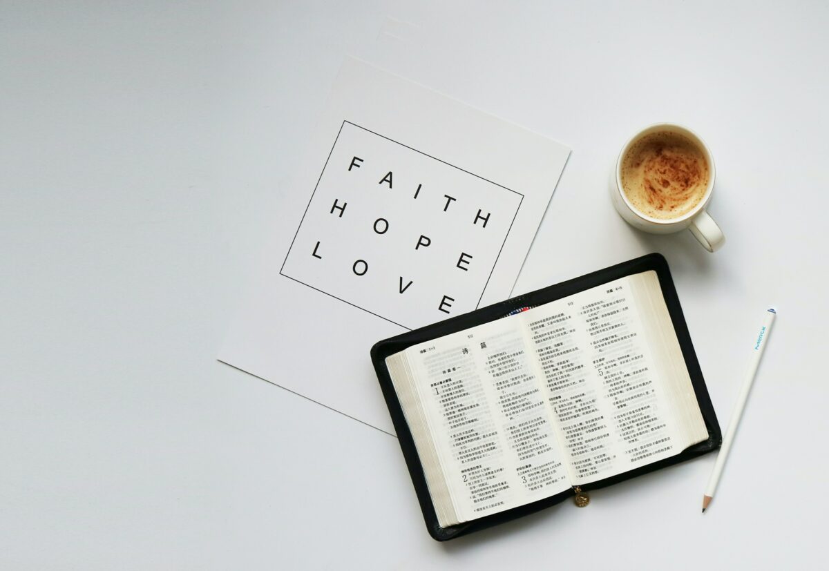 Image of open Bible, coffee mug, and a single piece of paper printed with the words, Faith, Hope, Love